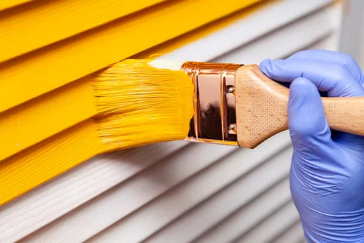 Brushing fresh enamel onto louvered trim on a Newhall home
