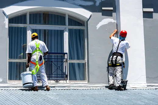 Two harnessed painters repainting a retail facade near Valencia Town Center